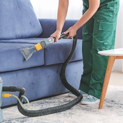 Man cleaning sofa pillow with steam cleaning in home